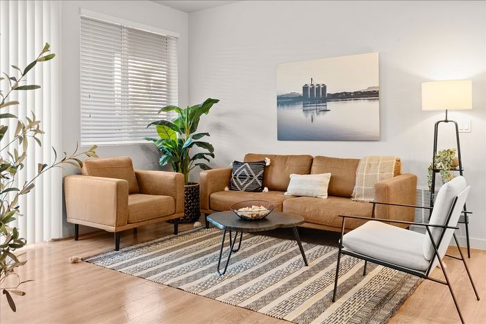 Inviting living room with a modern brown sofa set, stylish coffee table, and lush green plants, bathed in soft natural light.
