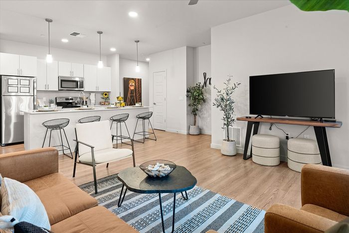 Contemporary open-concept living area with a chic kitchen, stylish bar seating, modern appliances, and cozy lounge space.