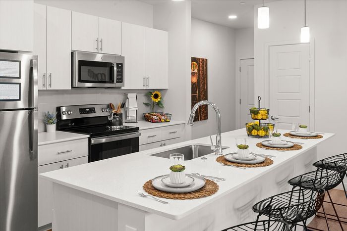 Modern kitchen design with sleek white cabinetry, stainless steel appliances, and a chic island breakfast bar with stylish place settings.