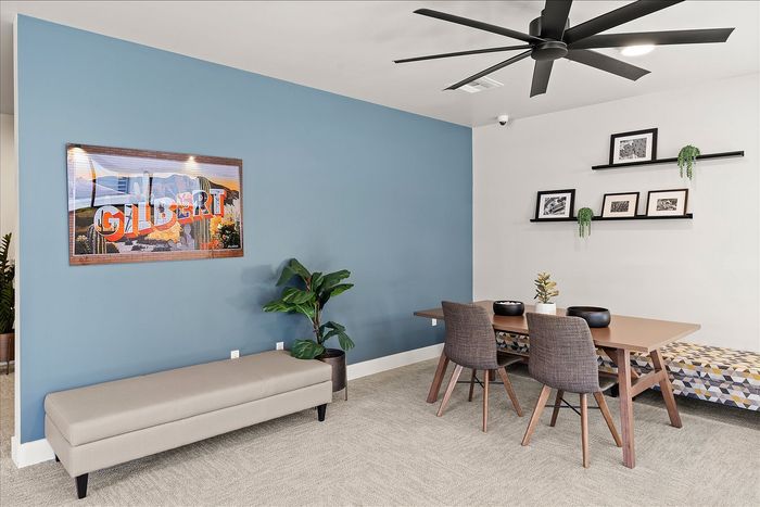 Chic work area with a modern table, stylish chairs, indoor plant, and vibrant artwork on a blue accent wall.