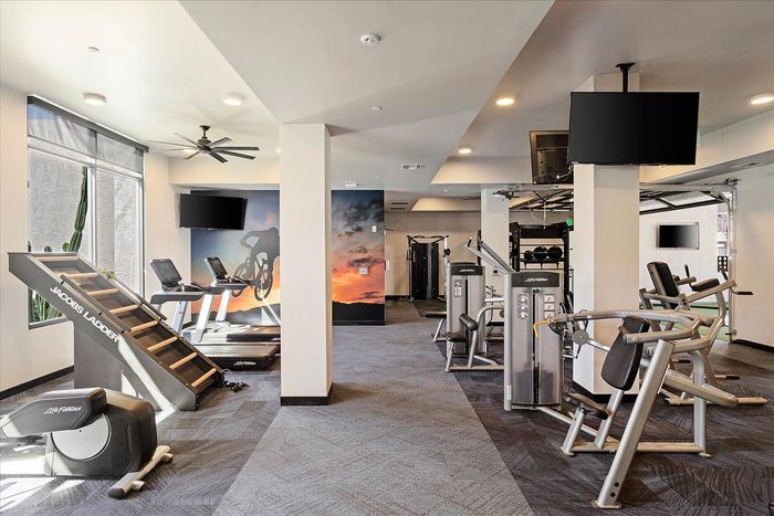 Spacious and modern gym with state-of-the-art fitness equipment, including treadmills and strength machines, enhanced by natural lighting and stylish d&eacute;cor.