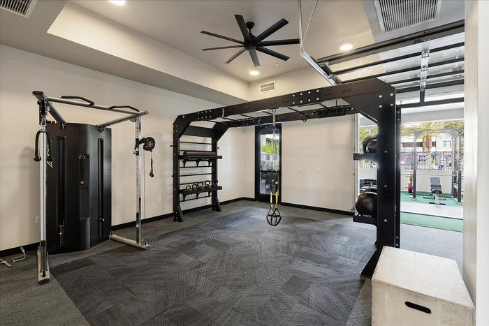 Modern fitness room with premium exercise equipment, featuring a sleek pulley machine, versatile workout station, and a TRX suspension trainer for diverse workouts.