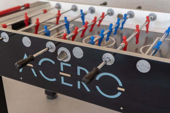 Sleek foosball table with vibrant red and blue players, perfect for exciting game nights at the Acero apartments.