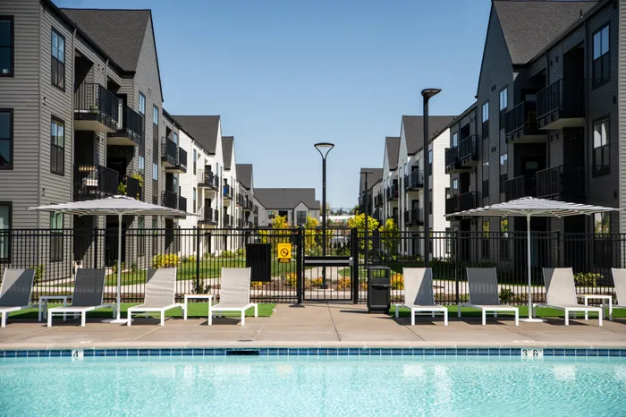 Elegant apartment complex with modern balconies, lush landscaping, and inviting poolside view, perfect for relaxation.