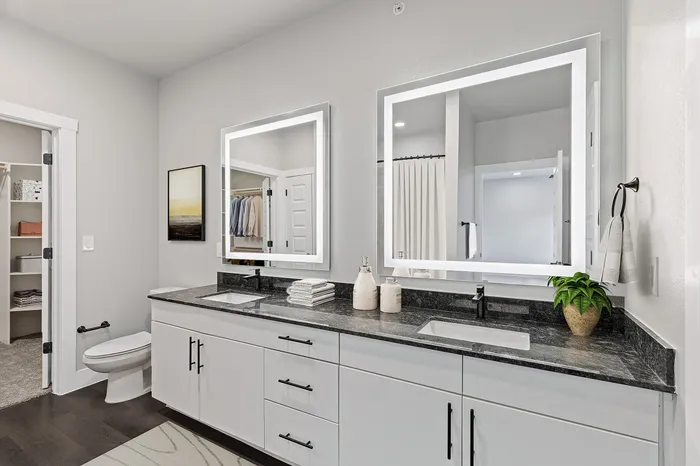 Well lit bathroom with a double vanity and spacious closet
