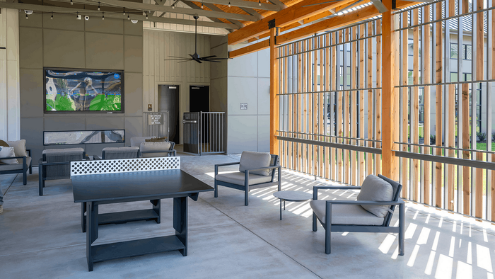 Spacious modern outdoor lounge area with stylish seating, wood accents, and a large TV for entertainment.