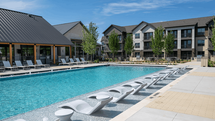 Luxurious apartment complex with stunning pool, modern sun loungers, and elegant architecture offering a serene retreat.