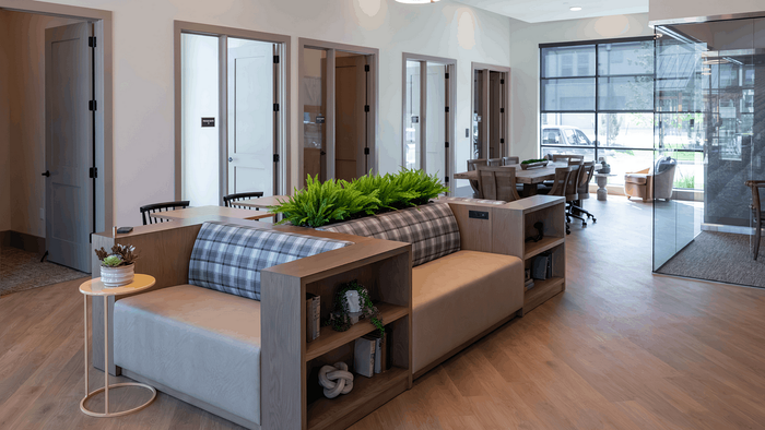 Contemporary office lounge featuring stylish seating, indoor plants, and abundant natural light through glass walls.
