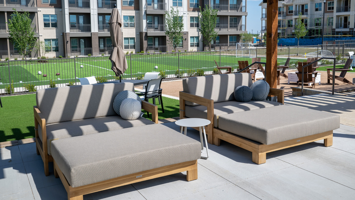 Luxurious outdoor lounge with plush seating and picturesque view of landscaped lawn, perfect for relaxation and recreational activities.