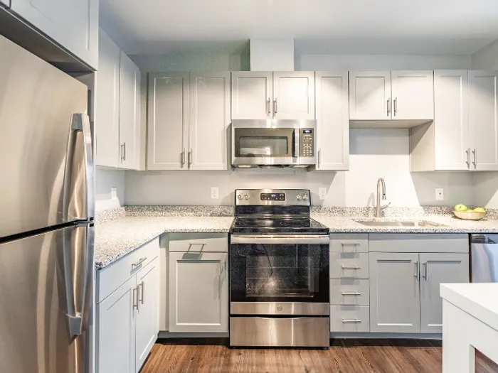 White-on-white kitchen with stainless steel appliances  in a model apartment at The Chandler Bedford, NH apartments.