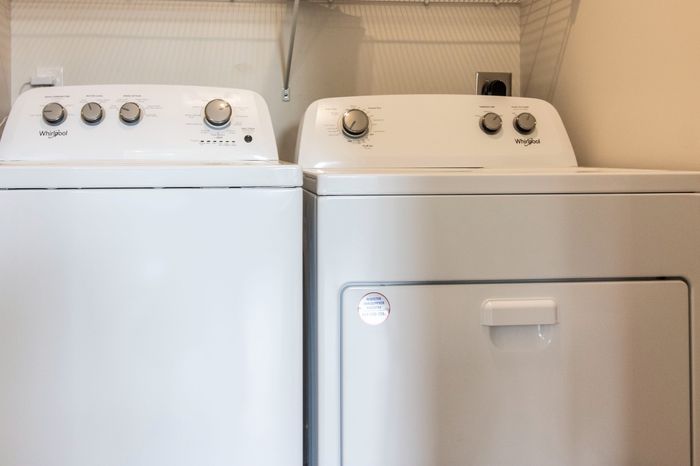 The James Apartments | Laundry room with a matching white Whirlpool washer and dryer set under a wire shelf | Luxury Apartments in Haverhill MA