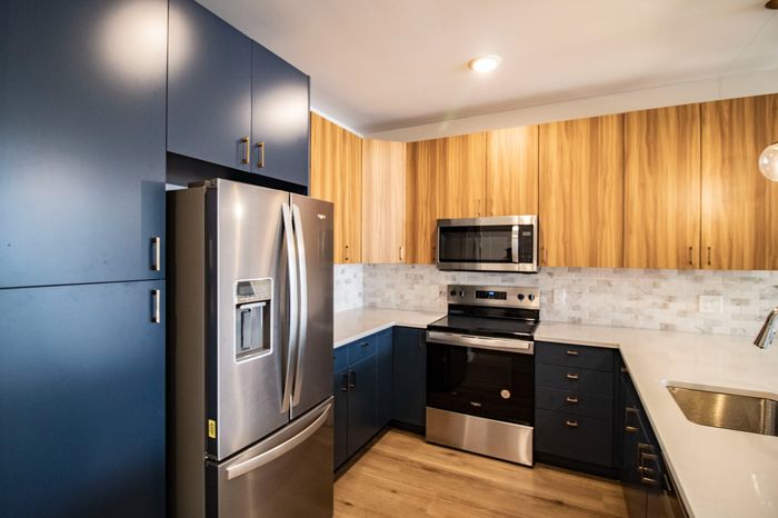 The James Apartments | Spacious kitchen with a stainless steel refrigerator, microwave, and oven, complemented by wooden cabinetry and a quartz countertop | Luxury Apartments in Haverhill MA