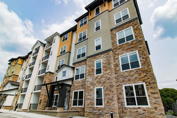 The James Apartments | Exterior view of a modern multi-story apartment building with stone accents and mixed siding, featuring large windows and balconies | Luxury Apartments in Haverhill MA