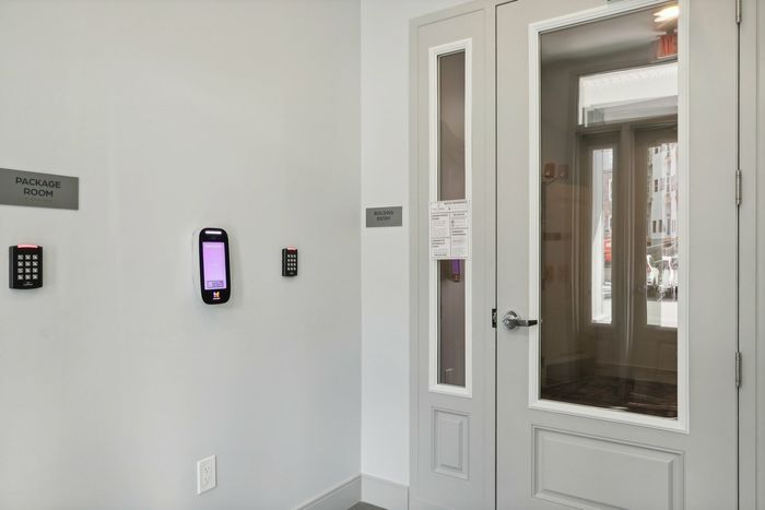 The James Apartments | Secure apartment building entryway with ButterflyMX access system and a digital screen displaying ‘Welcome.' The entry is adjacent to a package room sign | Apartments for Rent Haverhill MA