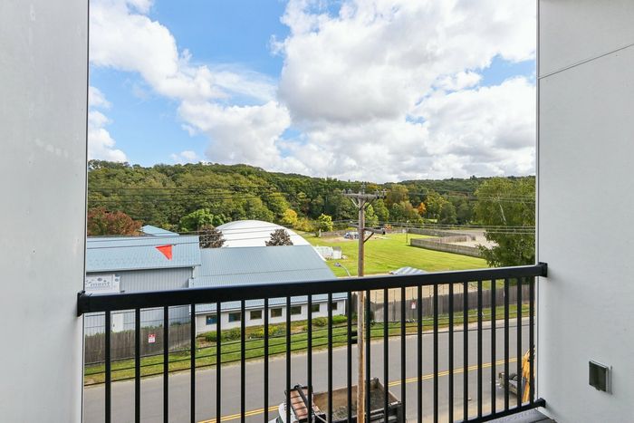 The James Apartments | Private balcony with a railing, offering a scenic view of green hills, rooftops, and a playground area in the distance. | Luxury Apartments Haverhill MA