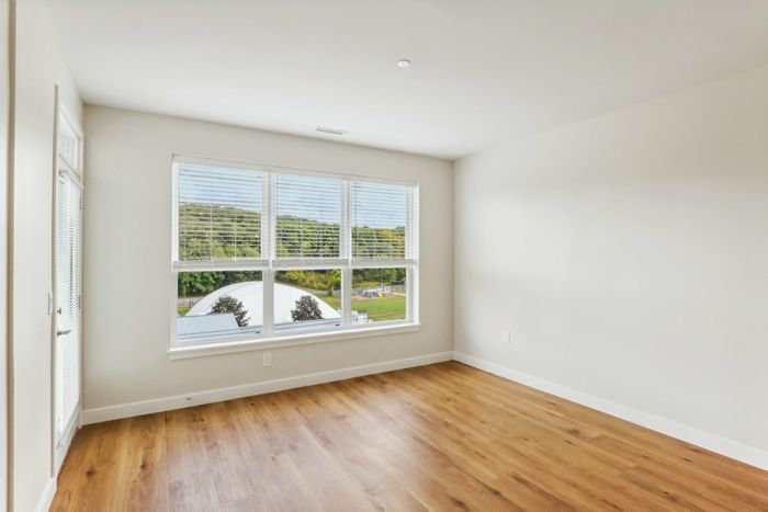 The James Apartments | Unfurnished room with hardwood flooring, large windows, and a scenic view of green hills and rooftops. | Luxury Apartments Haverhill MA