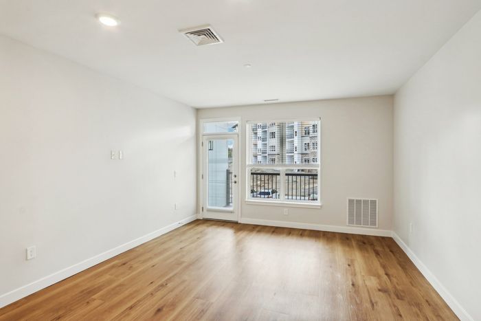 The James Apartments | Spacious unfurnished living room with large window, natural light, and a balcony door at 895 Boston Rd. | Luxury Apartments Haverhill MA