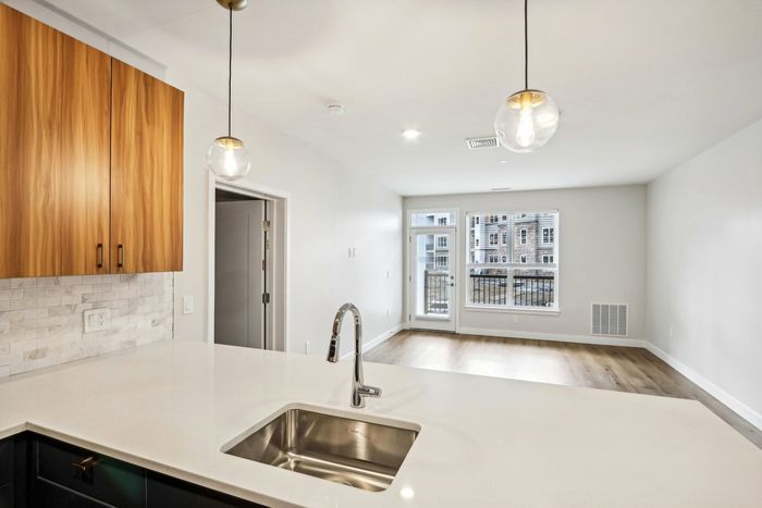 The James Apartments | Modern kitchen at 895 Boston Rd featuring wood cabinetry, stainless steel appliances, and a central island with a built-in sink. | Luxury Apartments Haverhill MA