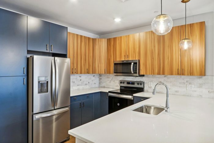 The James Apartments | Modern kitchen at 895 Boston Rd featuring wood cabinetry, stainless steel appliances, and a central island with a built-in sink. | Luxury Apartments Haverhill MA