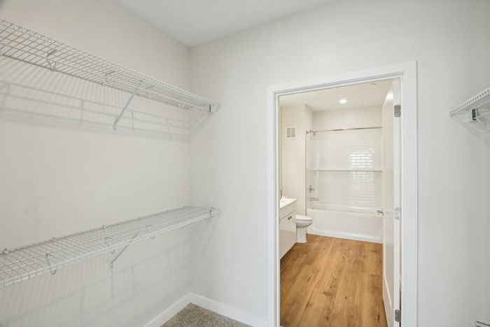 The James Apartments | Walk-in closet with wire shelving leading to a bathroom at 895 Boston Rd. | Luxury Apartments Haverhill MA