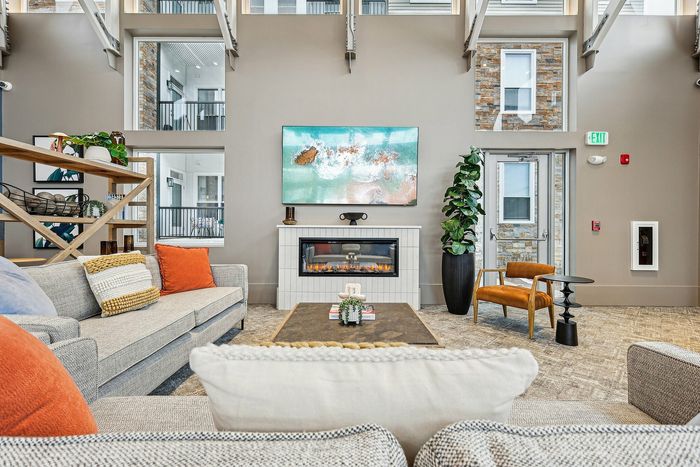 Elegant living room with stylish furniture, a vibrant painting above a sleek fireplace, and tall windows inviting natural light.
