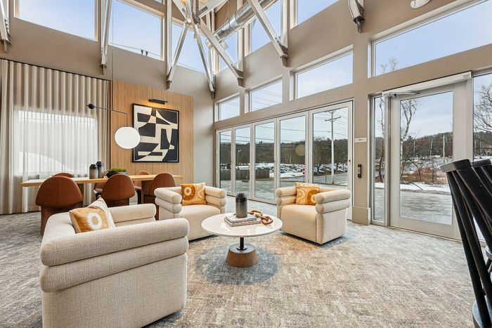 Bright and airy contemporary lounge with large windows, stylish beige seating, and a modern art piece.