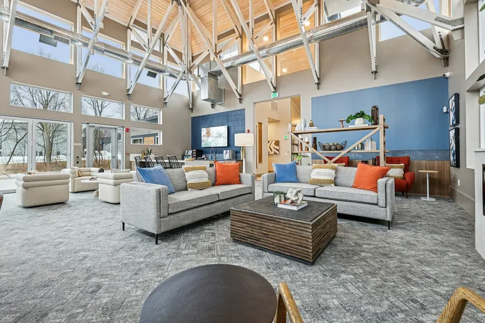 Spacious and stylish lounge area with high ceilings, large windows, and modern furnishings.