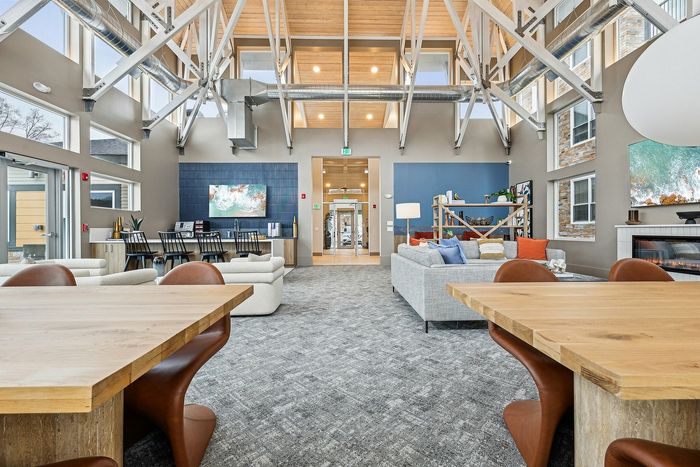 Spacious lounge with modern furnishings, high ceilings, and large windows for natural light.
