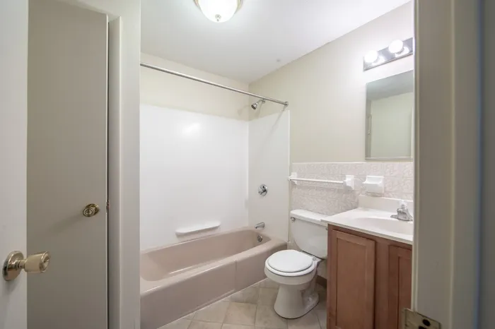 Elegant and well-lit bathroom featuring a sleek bathtub, modern vanity, and stylish lighting fixtures.
