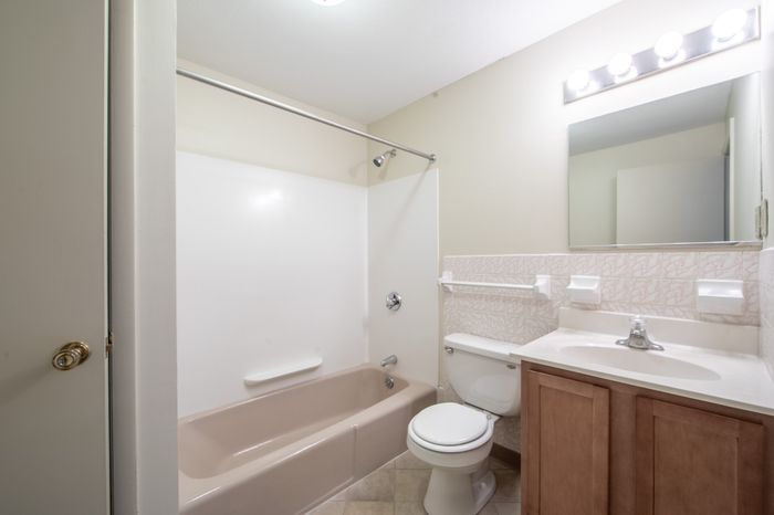 Bright and inviting bathroom featuring a clean bathtub, modern vanity, and soft lighting.