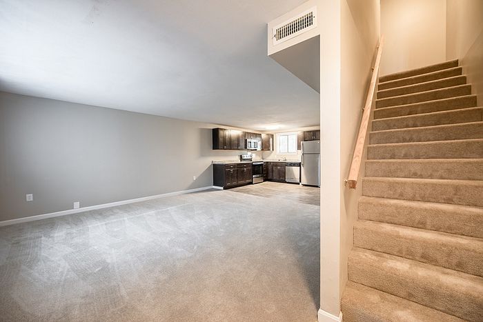 Bright and spacious open-concept living area with modern kitchen and inviting stairway, perfect for comfortable living.