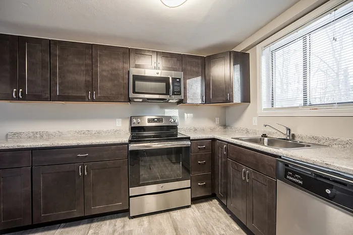 Modern kitchen with sleek dark wood cabinets, stainless steel appliances, and granite countertops.