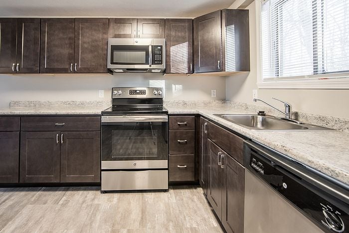 Modern kitchen with stainless steel appliances, sleek dark wood cabinets, and ample counter space, illuminated by natural light through large windows.