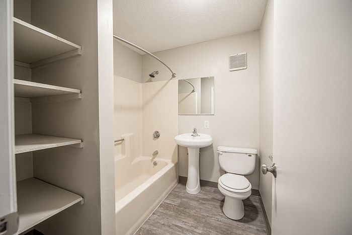 Modern bathroom featuring a sleek tub, elegant pedestal sink, and convenient built-in shelving.