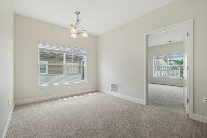 Beautiful natural light fills this spacious, carpeted room with large windows and a seamless flow into the next room at our pet-friendly apartments in Westford, MA. | Princeton Westford Apartments | Apartments with Balcony in Westford