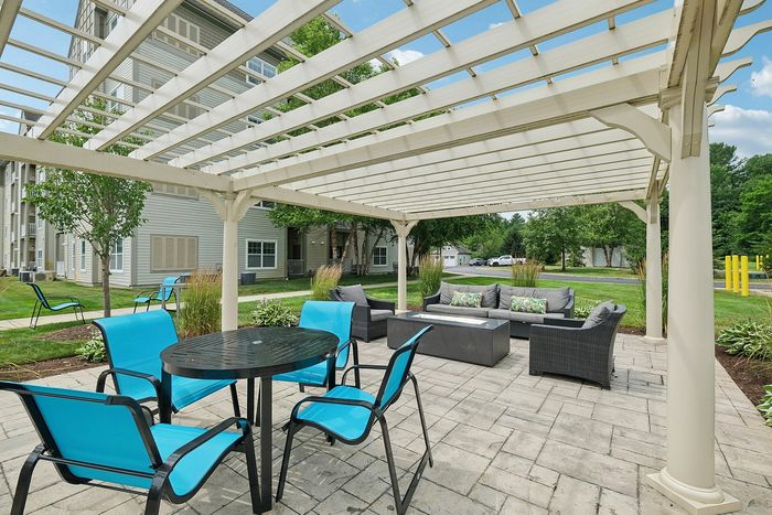 Dine al fresco under the pergola or grill up a meal next to the beautifully fenced swimming pool at our pet-friendly apartments in Westford, MA. | Princeton Westford Apartments | Wheelchair Accessible Apartments in Westford