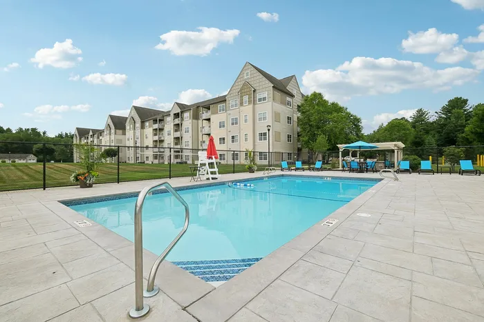 Sparkling outdoor swimming pool surrounded by a spacious sundeck and lounge chairs at our welcoming apartments in Westford, MA. | Princeton Westford | Luxury Apartments In Westford MA