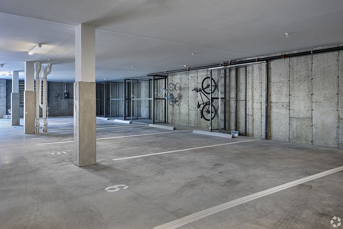 A clean, empty indoor parking garage at The James Apartments in Haverhill MA, featuring concrete floors and walls, numbered parking spaces, and two bicycles mounted on a wall rack.The James | Apartment in Haverhill, MA