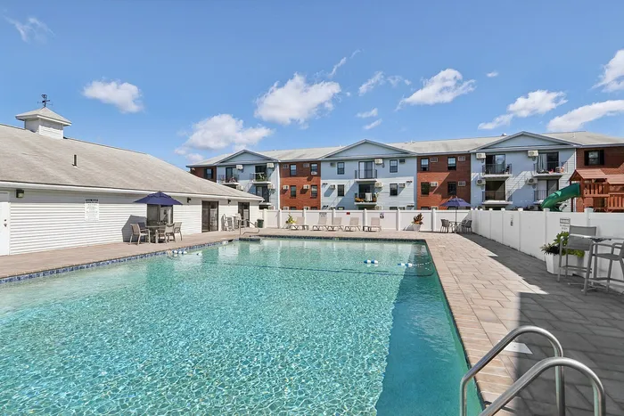Sparkling outdoor swimming pool surrounded by a spacious sundeck and lounge chairs at our pet-friendly apartments in Worcester, MA. | Princeton Place Apartments | Pet Friendly Apartments in Worcester