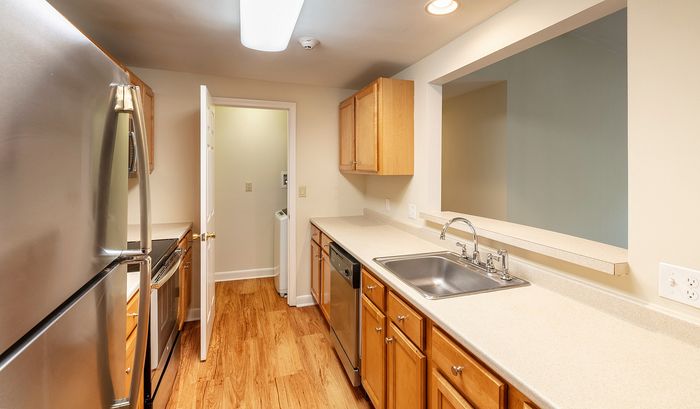 Contemporary kitchen with stainless steel appliances, sleek countertops, and inviting wood flooring.Your spacious kitchen offers generous square footage with room for multiple people and all your cooking essentials. | The Royal Crest | Apartment in,North Andover MA