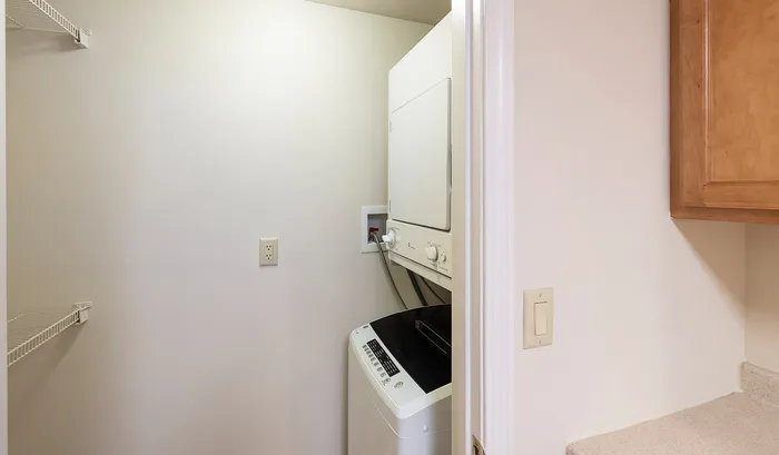Cozy laundry nook featuring a modern stacked washer and dryer, ample shelving, and efficient use of space.Your spacious kitchen offers generous square footage with room for multiple people and all your cooking essentials. | The Royal Crest | Apartment in,North Andover MA
