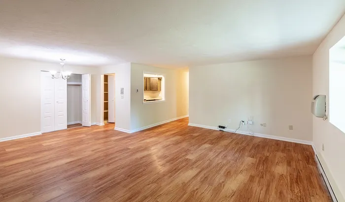 Inviting open-concept living area with elegant hardwood floors, ample natural light, and charming chandelier.Your spacious kitchen offers generous square footage with room for multiple people and all your cooking essentials. | The Royal Crest | Apartment in,North Andover MA