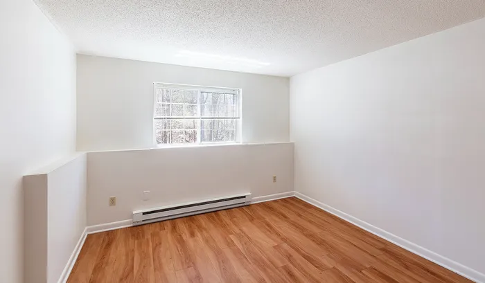 Bright, cozy room with sunlight streaming through a large window, highlighting elegant wood flooring and crisp white walls.Your spacious kitchen offers generous square footage with room for multiple people and all your cooking essentials. | The Royal Crest | Apartment in,North Andover MA