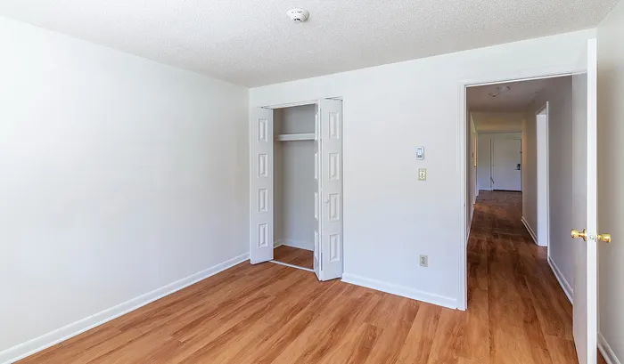 Bright empty room with elegant wood flooring and open closet, leading to a welcoming hallway with natural light.Your spacious kitchen offers generous square footage with room for multiple people and all your cooking essentials. | The Royal Crest | Apartment in,North Andover MA