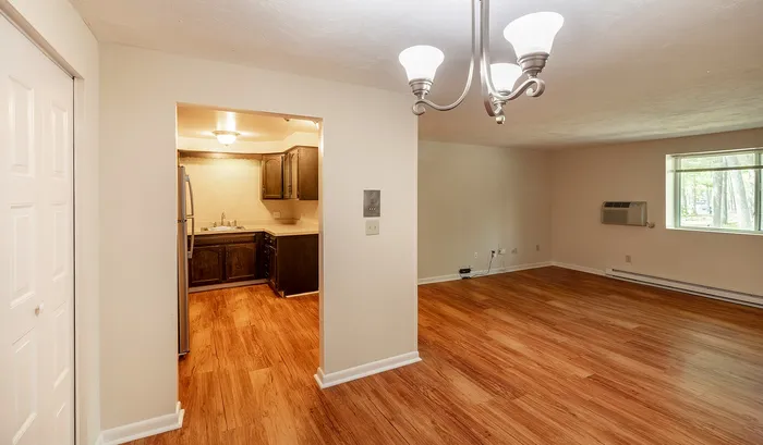 Bright and inviting open-plan living area with elegant hardwood floors, adjacent to a cozy kitchen with modern cabinetry and stainless steel appliances.Your spacious kitchen offers generous square footage with room for multiple people and all your cooking essentials. | The Royal Crest | Apartment in,North Andover MA