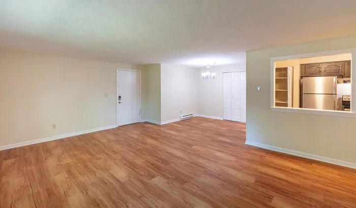 Inviting open-concept living space with elegant hardwood floors, a cozy dining area, and a modern kitchen through a pass-through window.Your spacious kitchen offers generous square footage with room for multiple people and all your cooking essentials. | The Royal Crest | Apartment in,North Andover MA
