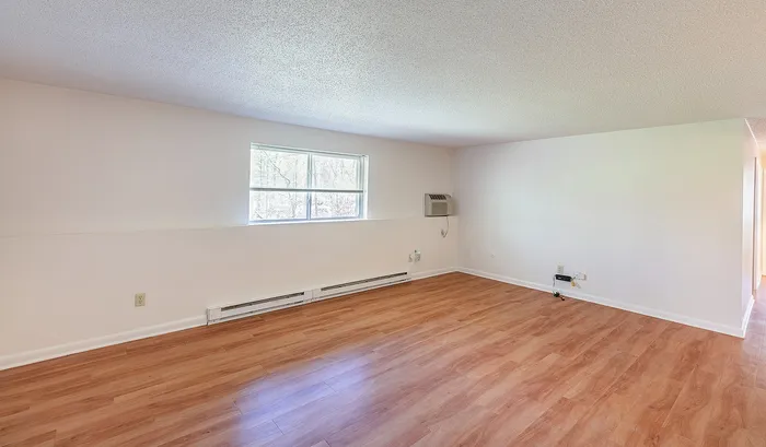 Bright and inviting living space with natural light, featuring elegant wood flooring and a large window for a serene view.Your spacious kitchen offers generous square footage with room for multiple people and all your cooking essentials. | The Royal Crest | Apartment in,North Andover MA