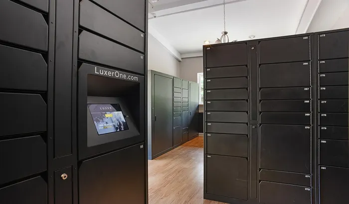 Modern package room featuring sleek black parcel lockers with a digital screen for secure and convenient deliveries | The Royal Crest | Apartment in North Andover, MA.
