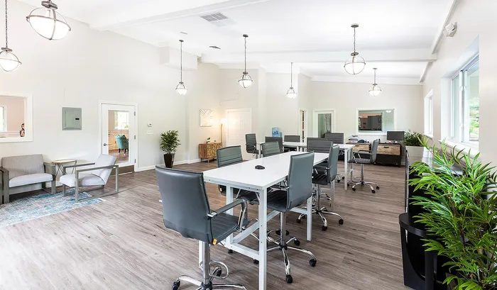 Bright and modern workspace featuring sleek grey chairs and tables, large windows, and vibrant greenery for a fresh atmosphere.| The Royal Crest | Apartment in North Andover, MA