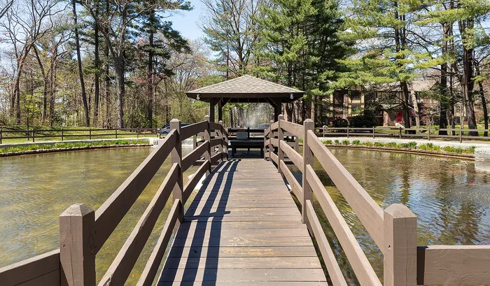Charming walkway over a serene pond leading to a cozy gazebo, nestled amidst lush trees and natural beauty.| The Royal Crest | Apartment in North Andover, MA